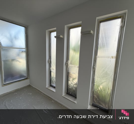 חדר עם חלונות מכוסים בניילון לקראת צביעה